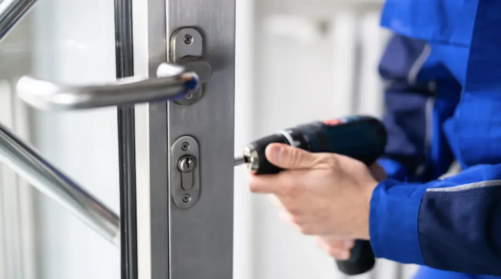Professional locksmith installing a door lock using an electric drill